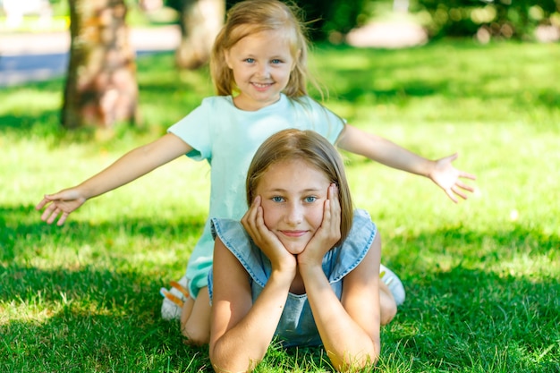 Dos hermosas hermanas en vestidos azules se encuentran en el césped del parque