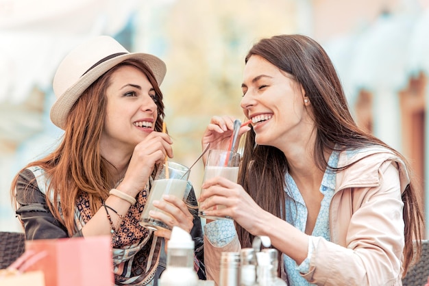 Dos hermosas mujeres bebiendo limonada y charlando en el café