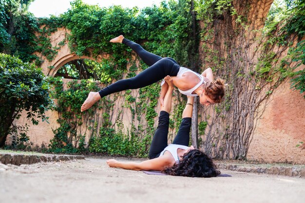 Dos hermosas mujeres haciendo acroyoga en el jardín o parque Armonía y relajación