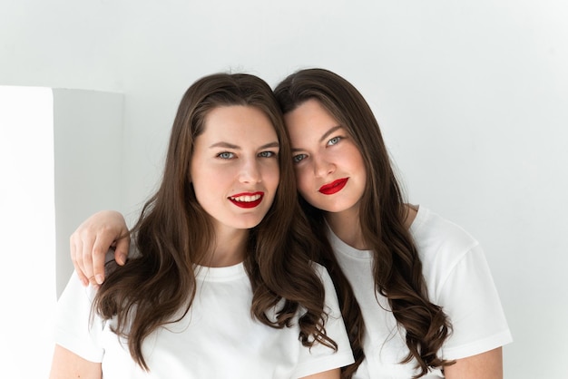 Dos hermosas mujeres hermanas gemelas posando fondo blanco.