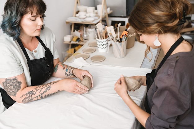 Dos hermosas mujeres jóvenes alfarero creando platos