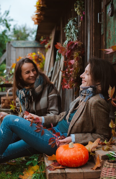 Dos hermosas mujeres jóvenes, cubriéndose la cara con una hoja amarilla de otoño, sonriendo