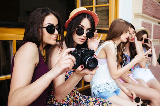 Dos hermosas mujeres jóvenes están sosteniendo una cámara vintage