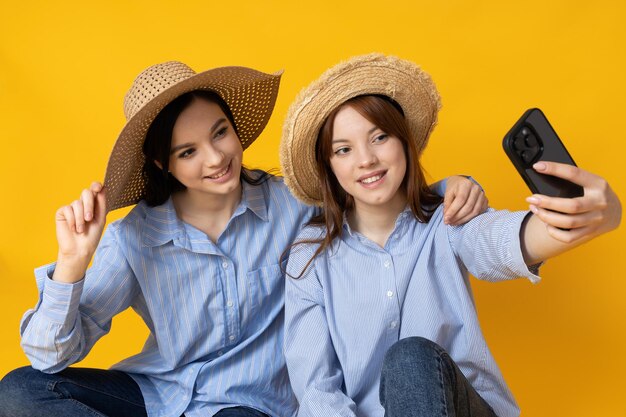 Dos hermosas mujeres jóvenes hermanas gemelas sobre fondo amarillo