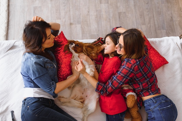 Foto dos hermosas mujeres jóvenes y una niña se encuentran en la cama en su casa cerca del árbol de navidad