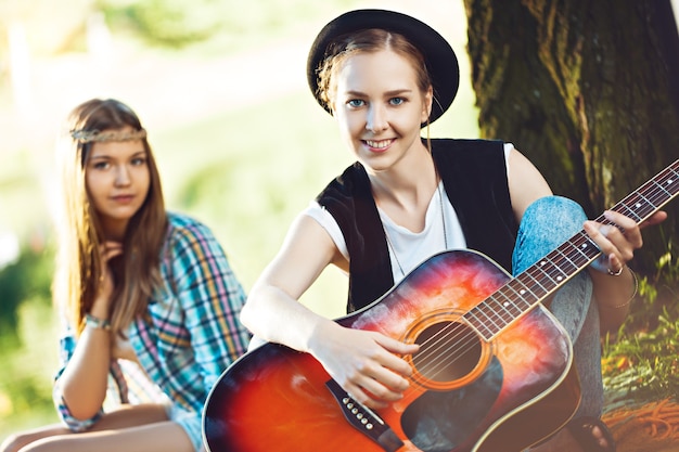 Dos hermosas mujeres jóvenes tocando la guitarra en un picnic