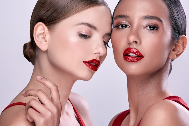 Dos hermosas mujeres con lápiz labial rojo, mujeres sexy con maquillaje, chicas guapas en rojo