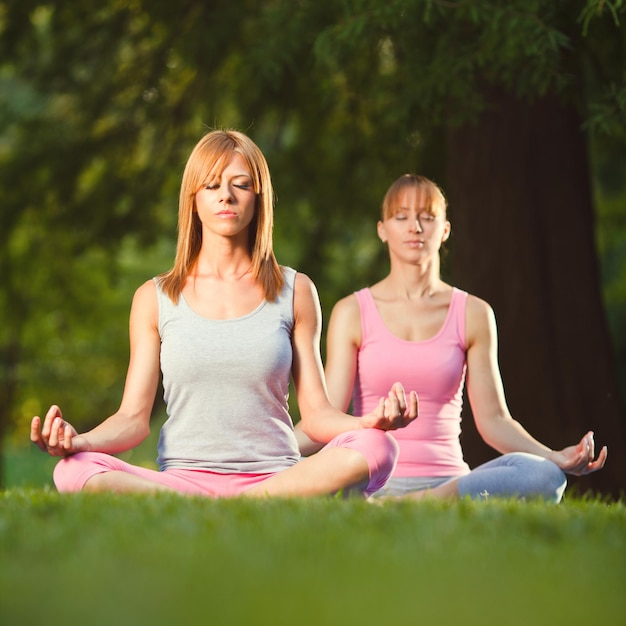 Dos hermosas mujeres meditando en el parque