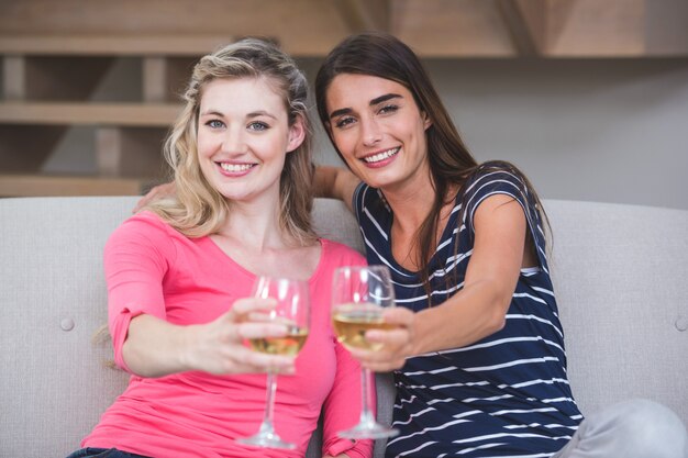 Dos hermosas mujeres mostrando su copa de vino en la sala de estar