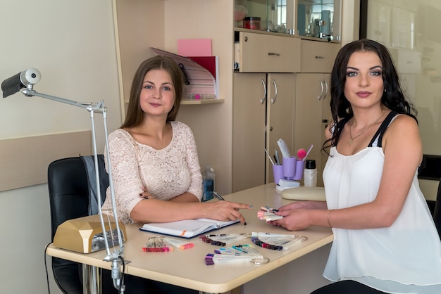 Foto dos hermosas mujeres en salón de belleza con paleta de uñas