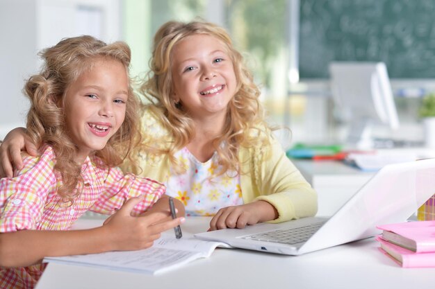 Dos hermosas niñas en clase usando laptop y escribiendo