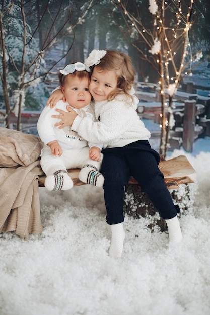 Dos hermosos niños caucásicos descansa con muchas luces a su alrededor en la noche de Navidad juntos