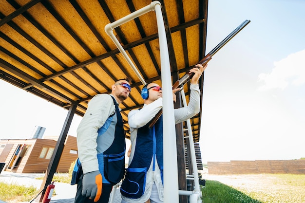 Dos hombres adultos con gafas de sol y un chaleco de rifle practicando tiro con armas de fuego