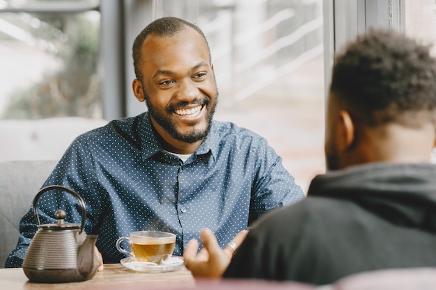 Dos hombres afroamericanos conversando con una taza de té. Amigo sentado en un café.