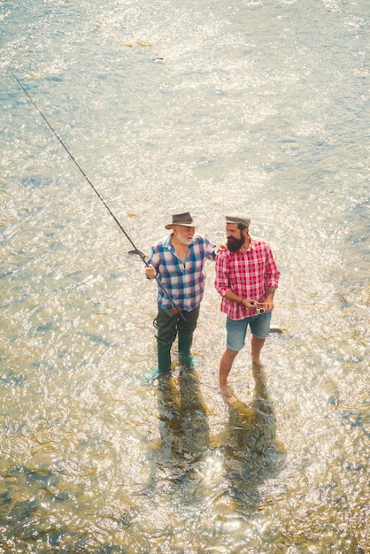 Dos hombres amigos pescador pescando en el río viejo padre e hijo con caña de pescar en riverside recreati