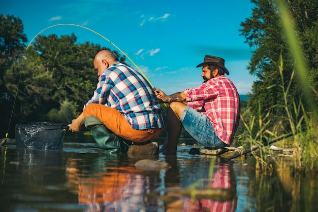 Dos hombres amigos pescador pescando en el río viejo padre e hijo con caña de pescar en riverside recreati