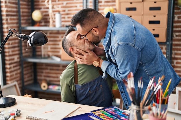 Dos hombres artistas dibujando en un cuaderno besándose en un estudio de arte