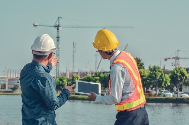 Dos hombres asiáticos hablando de proyectos de construcción de negocios al aire libre en el sitio de bienes raíces, gerente de proyectos, ingeniero de proyectos