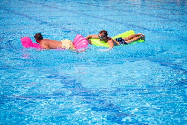 Dos hombres se bañan en la piscina y se relajan. Foto de alta calidad