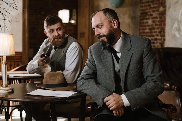 Dos hombres barbudos con trajes antiguos hablando o discutiendo algo en el restaurante