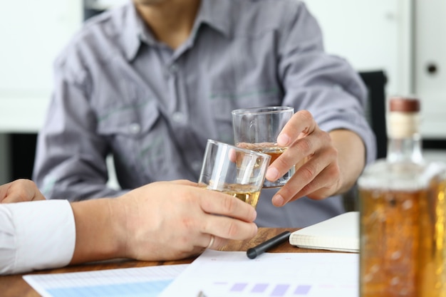 Dos hombres bebiendo whisky de vasos