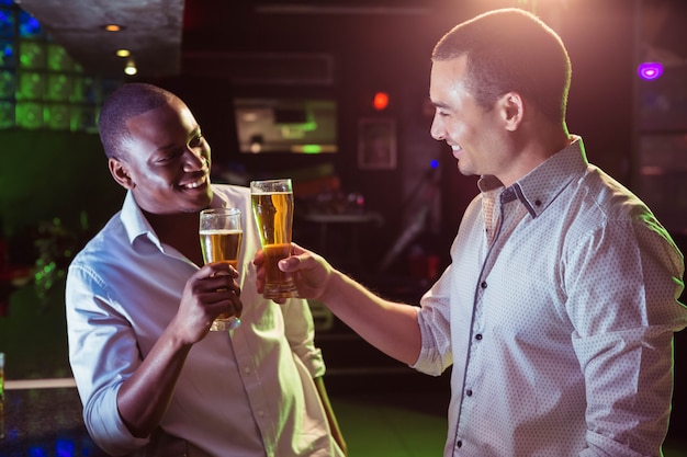 Dos hombres brindando con un vaso de cerveza en el bar