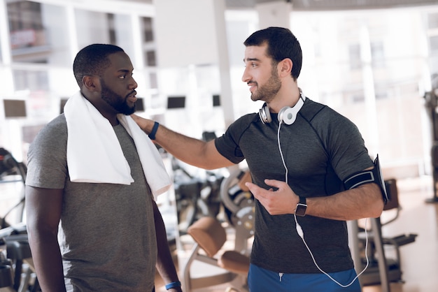 Dos hombres se comunican en los hipódromos del gimnasio.