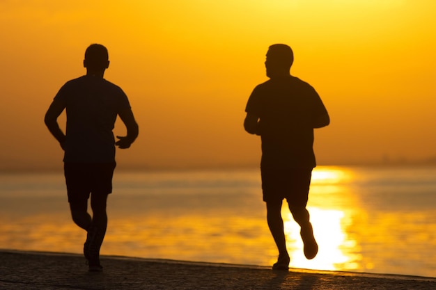 Los dos hombres corriendo al amanecer en la costa del río