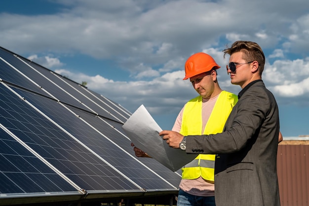 Dos hombres discutiendo el plan de instalación de la nueva estación solar Concepto de energía verde