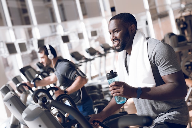 Dos hombres están ocupados en las cintas en el gimnasio moderno.