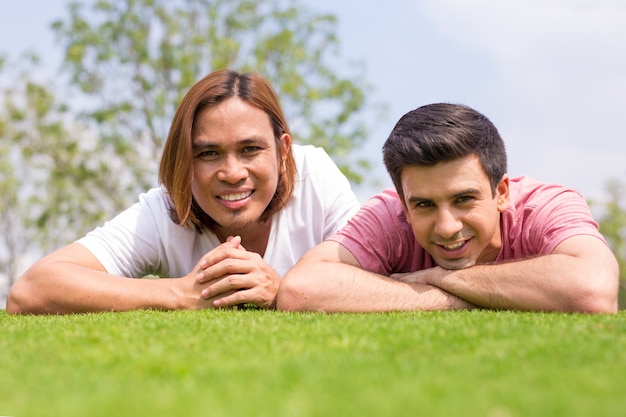 Dos hombres guapos sonrientes tumbados en la hierba