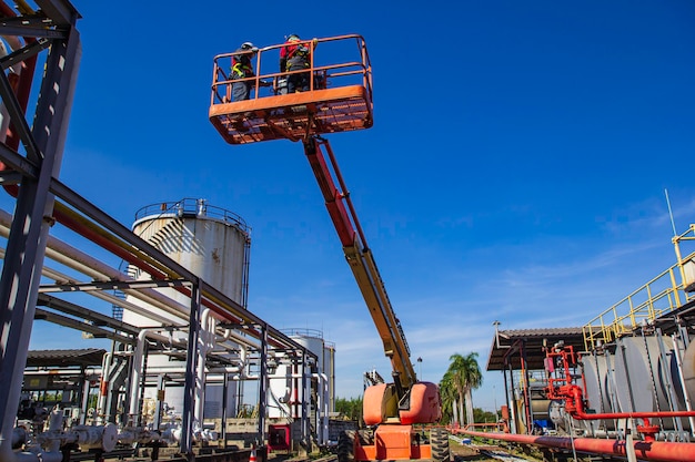 Dos hombres de la industria trabajando en lo alto de una inspección de elevación de la pluma de aceite de oleoducto