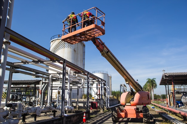 Dos hombres de la industria trabajando en lo alto de una inspección de elevación de la pluma de aceite de tubería