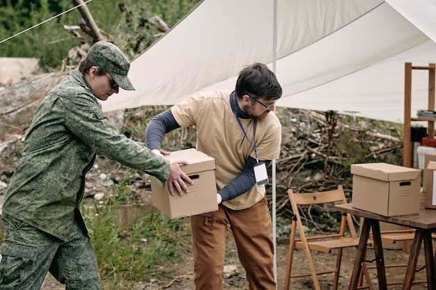 Dos hombres jóvenes entregando cajas con donación.