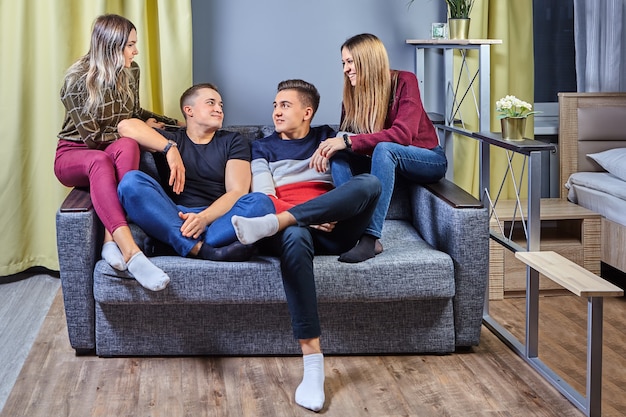 Dos hombres jóvenes están sentados en el sofá frente al televisor, las niñas distraen a sus novios de ver películas.