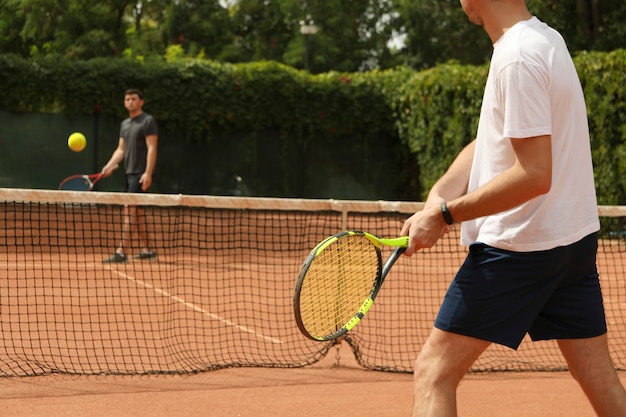 Dos hombres jugando al tenis en la cancha de arcilla