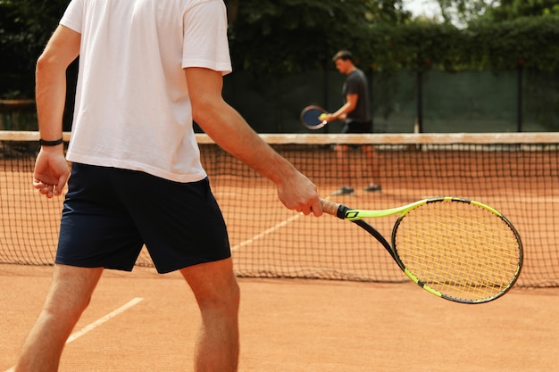 Dos hombres jugando al tenis en la cancha de arcilla