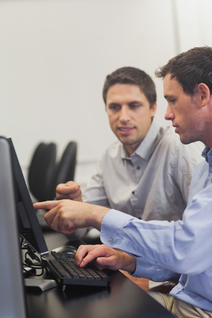 Foto dos hombres maduros hablando mientras está sentado frente a la computadora