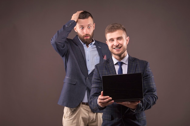 Dos hombres mirando portátil con sorpresa
