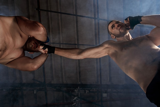 Dos hombres musculosos peleando, culturistas golpeándose entre sí, entrenando en artes marciales, boxeo, jiu jitsu y mma. concepto de kickboxing