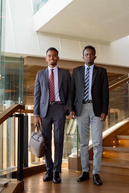 Dos hombres de negocios africanos con traje y corbata en la cafetería.