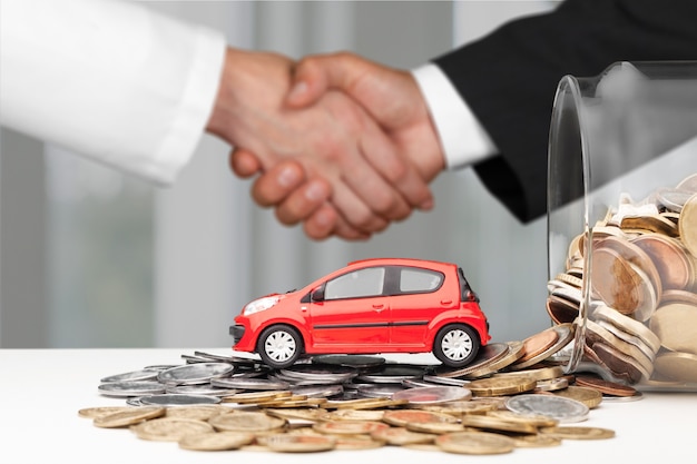 Foto dos hombres de negocios apretón de manos con monedas de coche y dinero. concepto de trato