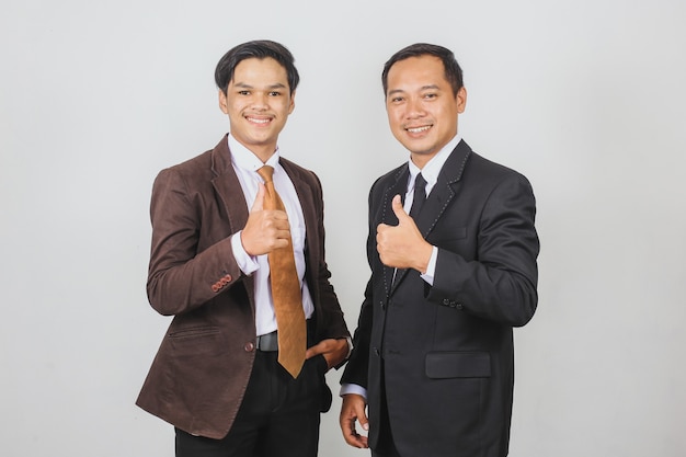 Dos hombres de negocios asiáticos en traje chaqueta y corbata posando junto con los pulgares para arriba gesto