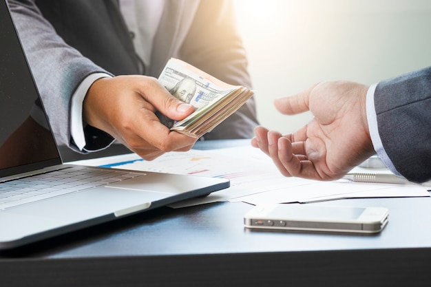 Foto dos hombres de negocios dan y toman billetes de dólar estadounidense. el dólar estadounidense es la moneda de cambio principal y popular en el mundo. inversión y pago