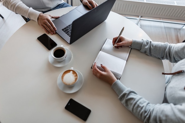 Dos hombres de negocios discuten momentos de trabajo y beben café mientras están sentados en una mesa en un café