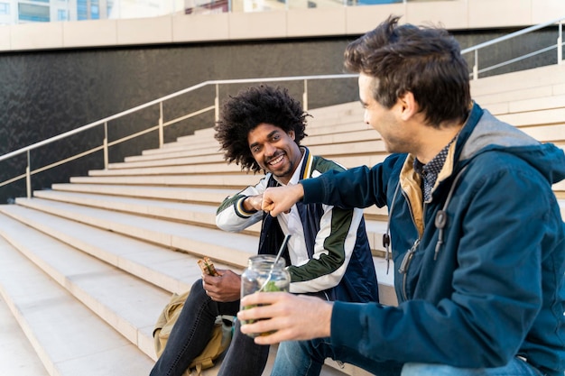 Dos hombres de negocios felices sentados en las escaleras teniendo un descanso para almorzar.