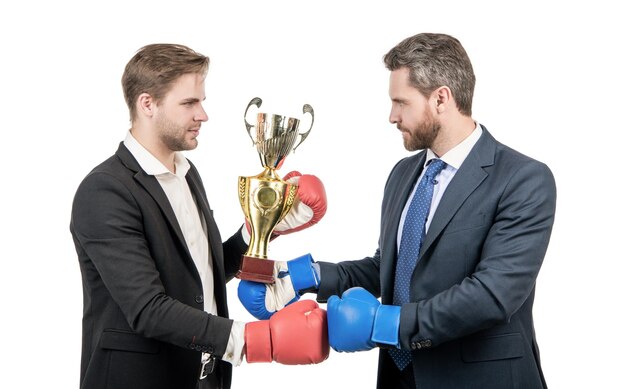 Dos hombres de negocios en guantes de boxeo sostienen la copa de campeón después de la batalla por el oponente ganador del liderazgo