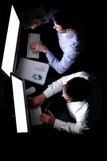 Dos hombres de negocios haciendo un informe financiero por la noche el concepto de horas extras
