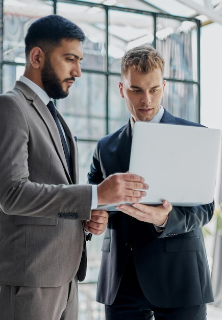 Dos hombres de negocios profesionales discutiendo y usando una computadora de escritorio en la oficina