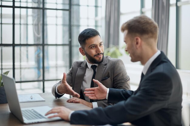 Dos hombres de negocios profesionales discutiendo y usando una computadora de escritorio en la oficina